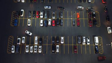 Bir otoparkın tepeden aşağı görüntüsü, bir çok araba, şehir ulaşımı ve şehir altyapısı, akşam ışığı.