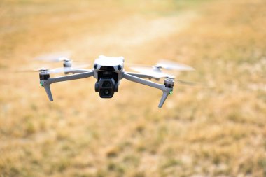 Modern kuadkopter dronu altın bir tarlanın üzerinde havada uçuyor. Görüntü, görüntü ve izleme için kullanılan yüksek teknolojili hava aygıtı..