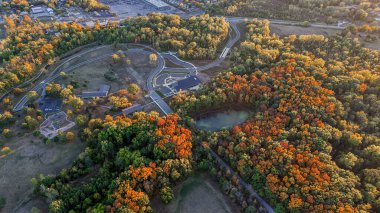 Sonbahar ormanı ve şehir parkının gökyüzü manzarası. Sonbahar mevsiminde binalar, yollar ve renkli ağaçlar..