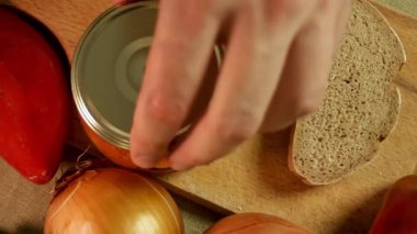 Bıçak nazikçe kavanozdan yayılır, canlı dokuyu ve zengin rengi ortaya çıkarır. Etrafı sebzelerle çevrili olan yayılma, köy hazırlıklarının merkezi haline gelir. Yayılma kavramı ve eller yemek ritüeli..