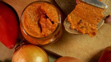 Elleri ekmeğin üzerine yapıştırır, yumuşak ekmek dokusunu sıcak ev yapımı aromayla harmanlar. Ekmek hamurla nazikçe birleşerek basit bir sandviç oluşturur. Ekmek ve el kavramı konforlu yemek ritüeli olarak kabul edilir.