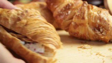 Erkek eller kahvaltı masasından kruvasan kaldırır, ayçöreği dokusunu ve jestini gösterir. Kruvasan ısırık iziyle geri döndü. Kahvaltıda kruvasan kavramı kişisel bir andır..