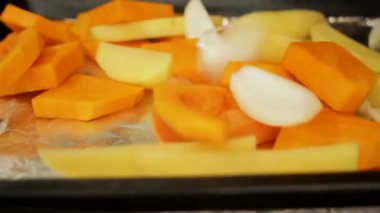 Sebzeler fırın tepsisine düşer. Parlak renkli balkabağı, havuç, soğan ve patates fırında. Yüksek kaliteli FullHD görüntüler