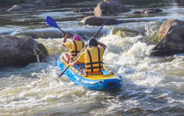 Dağ nehrinin beyaz sularında gezen iki adam. Konsept: ekstrem su sporları, aktif dinlenme, aşırı rafting. Arka plan.