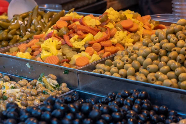 Pickles (olives, carrot and yellow cauliflower) on a white plate and a blue table - close , Salting olives carrots cauliflower.