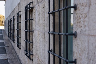 Beyaz arka planda paslı dövülmüş parmaklıkları olan eski pencere. Pencereler büyük siyah parmaklıklarla dolu..