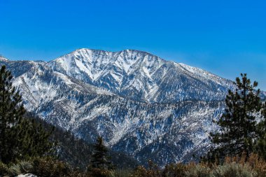 Güney Kaliforniya 'daki San Gabriel Dağları, kışın karla kaplı. Yukarıda açık mavi gökyüzü.