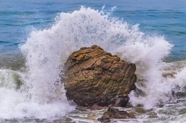 California, Malibu 'da Leo Carrillo sahilinde dalgalar kayalara çarpıyor. Sprey havaya uçuyor. Arka planda Mavi Pasifik Okyanusu. 