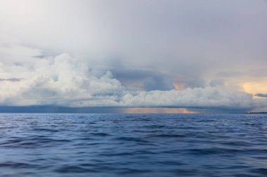 Kuzey Bali kıyılarında okyanus boyunca görülen uzak bir fırtına. Uzakta gök gürültülü bulutlar; geride kalan sağanak yağmur. 