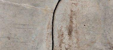 Yıpranmış beton duvarlar yüzeylerinde doğal çatlaklar ve kusurlar gösteriyor..