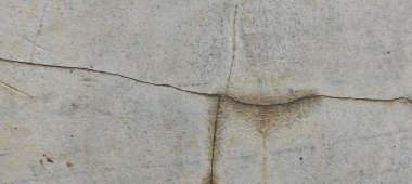 Yıpranmış beton duvarlar yüzeylerinde doğal çatlaklar ve kusurlar gösteriyor..
