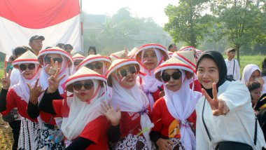 Bir grup coşkulu insan Endonezya Bağımsızlık Günü geçit törenine geleneksel kıyafetler ve kırmızı ve beyaz tişörtler giyerek katıldılar..
