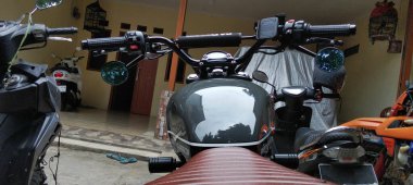 Triumph motorsikletinin gidonu ve tankı arkadan görülüyor..