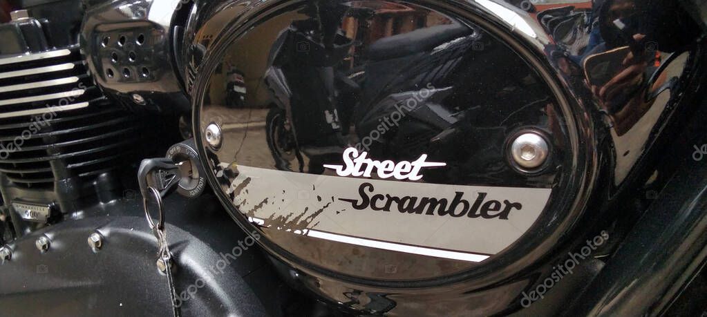 The Triumph Street Scrambler motorcycle features a gloss black side cover with the signature 