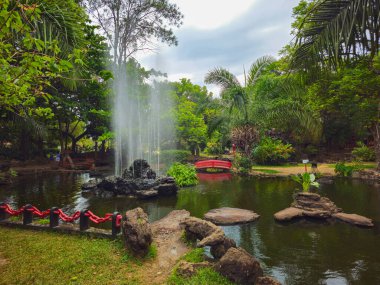 Sakin bir tropikal Japon tarzı bahçe, sakin bir göletin etrafında sergilenir ve burada merkezi bir kaya çeşmesi havaya hafif su akıntıları gönderir. Bereketli tropikal yeşillikler, palmiyeler ve dikkatlice yerleştirilmiş bitkiler olay yerinin etrafını sarar.