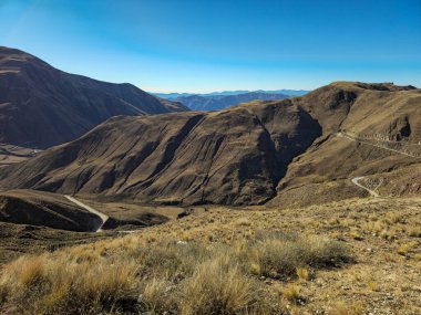 Arjantin, Salta 'daki Cuesta del Obispo boyunca uzanan engin yüksek irtifa manzarası, erozyon ve zaman tarafından yontulmuş dönen And sırtlarını ortaya çıkarıyor. Dar bir viraj yolu kuru vadileri kesiyor.
