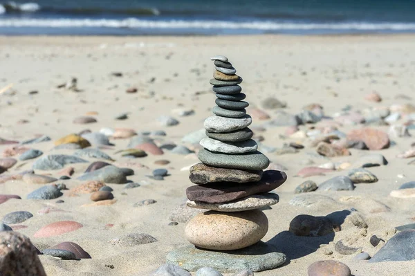 stones on the sea sand, sea stones stacked one on top of another, a pyramid of flat stones