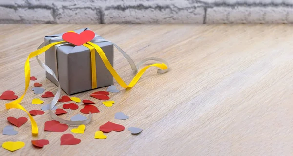 valentine\'s day february 14, birthday gift, congratulate on the holiday, give a gift, grey gift with yellow ribbon, grey packaging with red ribbon, valentine\'s day decor