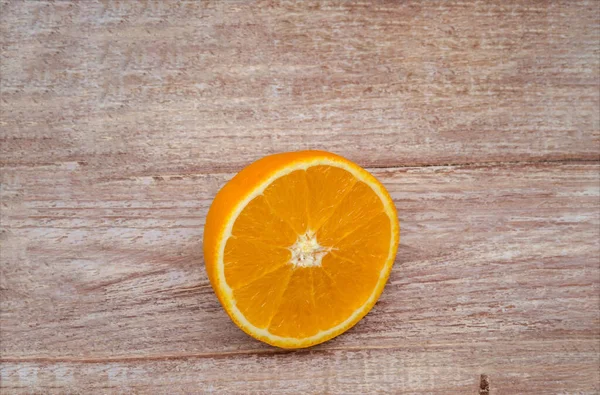 Half an orange on a wooden table. Orange on a wooden background. Banner with orange.
