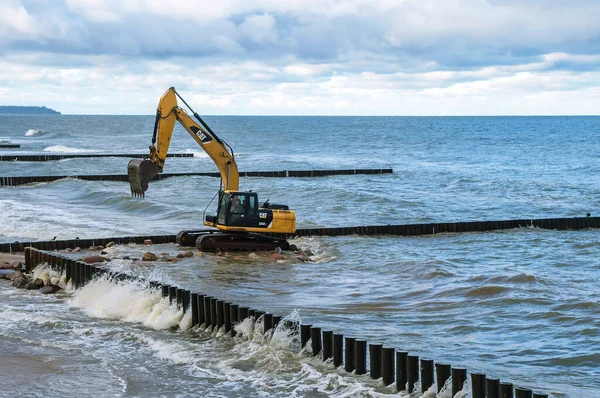 Baltic Sea, Kaliningrad region, Russia, November 29, 2020. Construction of breakwaters in the sea. Construction equipment and machinery on the seashore.