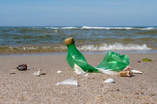 Pollution of the coast with plastic bottles. Garbage on the beach. Plastic on the beach. Green empty bottle.