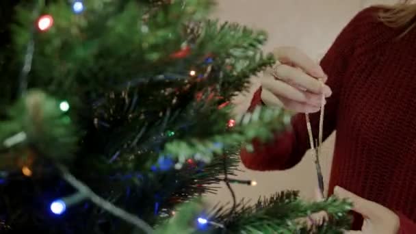 Ξανθιά γυναίκα στο κόκκινο πουλόβερ διακοσμήσετε το χριστουγεννιάτικο δέντρο με Χριστούγεννα ελάφια — Αρχείο Βίντεο