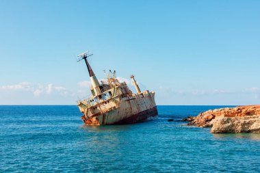 Yıpranmış, paslanmış Edro III gemi enkazı sakin mavi suyu ve parlak gökyüzüyle kayalık bir kıyıya dayanır. Bu görüntü yalnızlığı, çürümeyi ve denizin ebedi gücünü anımsatıyor..