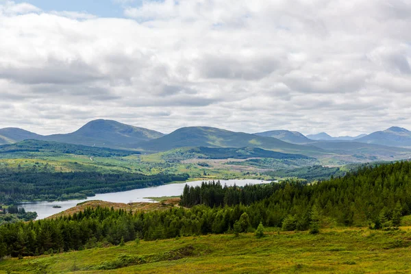 Skye Adası, İskoçya - Yeşil tepeler, dolambaçlı bir göl, sık ormanlar ve bulutlu bir gökyüzünün altındaki uzak dağlardan oluşan sakin bir manzara. Doğa, seyahat, açık hava yaşam tarzı ve manzara için ideal..