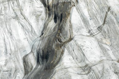 Akan damarları ve yıpranmış desenleri olan gri ve beyaz mermer kayaların yakın görüntüsü. Bu doğal taş yüzey, arka plan veya doku odaklı projeler için uygun engebeli manzaraları, jeolojiyi ve soyut sanatı çağrıştırır..