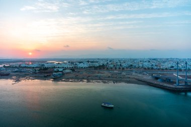 Sur 'da günbatımı. Sur şehrinin batısına bakın. Uzaktan Dhow faktörü. Sur, Umman.