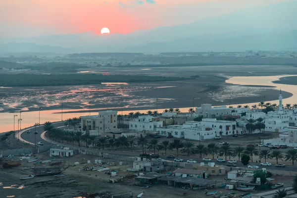 Sur 'da günbatımı. Sur şehrinin batısına bakın. Uzaktan Dhow faktörü. Sur, Umman.