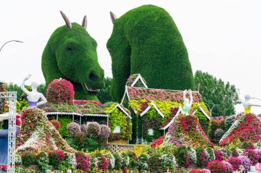Dubai, Birleşik Arap Emirlikleri, BAE - 27 Mart 2024: Dubai Mucize Bahçesi, Dubai 'deki en popüler turistik merkezlerden biri. Çiçek heykelleri ve çiçeklerle çevrili büyük yeşil at çalı çiçeklerinin yer aldığı muhteşem bir bahçe sergisi.