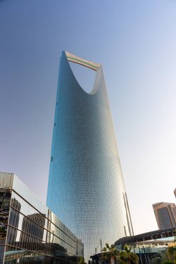 Riyad, Suudi Arabistan - 1 Ocak 2026: Riyad 'daki Krallık Merkezi' nin çarpıcı mavi camdan gökdeleninde parlak bir gökyüzüne karşı açılan kavisli bir kemer yer alıyor. Günümüz kulesi şehir manzarasına hükmediyor, güneş ışığını yansıtıyor ve B 'nin etrafını sarıyor.