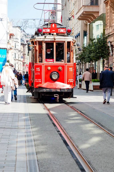 İstanbul, Türkiye. 15 Nisan 2022: Istiklal Bulvarı 'nda, yayalar ve tarihi binalarla çevrili, kalabalık bir şehir caddesi boyunca parlak bir nostaljik tramvay süzülüyor. Sahne, şehir yaşamını, seyahatleri ve ikonik toplu taşımayı canlı olarak yakalıyor.
