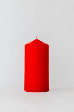 Ev dekorasyonu için büyük bir kırmızı mum yakın plan. Beyaz bir arka planda, rahat ve sakin atmosferi temsil eden stüdyo ışıkları.