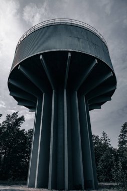 Sonbahar ağaçları tarafından karamsar ışıkta çerçevelenmiş eski bir su kulesinin dramatik yukarı açısı.