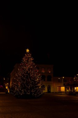 Şehir merkezinde dikilen büyük bir Noel ağacının gece manzarası festival ışıkları ve kış atmosferiyle çevrili..