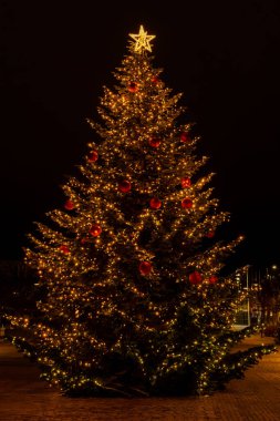 Güzel dekore edilmiş bir Noel ağacının, şehir merkezinde gece vakti, tatil sezonunda parlayan yakın görüntüsü..