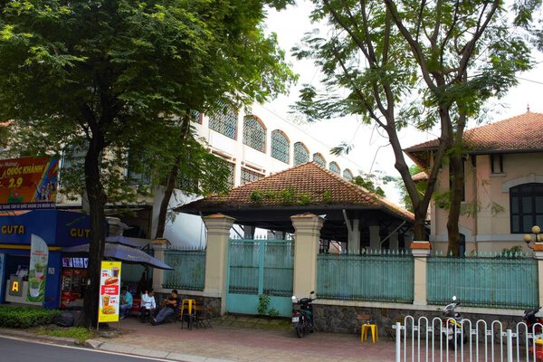 Photo of Le Quy Don High School  in Ho Chi Minh City, Vietnam on November 9th 2025 : An ancient building with  French style architecture at the corner of the street with many tree surrounding