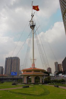 Ho Chi Minh City, Vietnam 'daki Bach Dang Wharf' ın 5 Aralık 2025 'teki fotoğrafı: Vietnam ulusal bayrağı Vietnam' ın Ho Chi Minh şehrinin merkezindeki Bach Dang Wharf Park 'ta dalgalanmaktadır. Ufuk çizgisi ve modern şehir geçmişi olan şehir parkı manzarası.