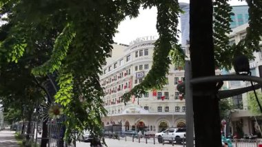 Ho Chi Minh City, Viet Nam 'daki Bach Dang Wharf' ın 15 Aralık 2025 'teki videosu: Majestic Hotel' in manzarası Saigon şehir merkezinde rüzgarda savrulan yaprakların arkasında. Bu otel Saigon 'un en eski ve ünlü otellerinden biridir..