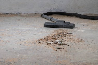 Tozlu beton zeminde döküntülerle dolu bir elektrikli süpürge kafası..