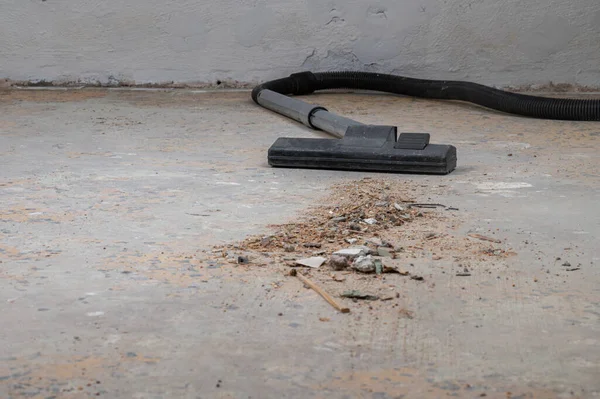 Tozlu beton zeminde döküntülerle dolu bir elektrikli süpürge kafası..