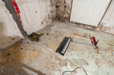 Enkaz, süpürge ve kırık lambayla terk edilmiş bir oda..