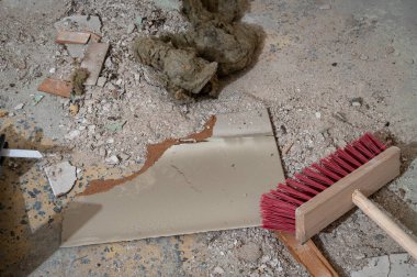 Yerlerde süpürge ve yalıtım malzemeleriyle inşaat enkazı.