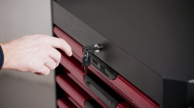 Bir atölyedeki alet çantası çekmecesinin kilidini açmak, güvenli araç deposu, erişim kontrolü ve işyeri güvenliği kavramı