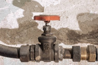 Duvarda kırmızı saplı paslı su vanası.