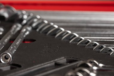 Bir araç çekmecesine yerleştirilmiş metal anahtarların seçici odak noktası, dokuyu, hassasiyeti ve sığ bir alan derinliği ile organize atölye depolama