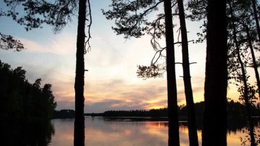 Sıcak günbatımı ışığı sakin suyu yansıtan bir orman gölünün yanında. Huzurlu İskandinav manzarası sessizliği, dengeyi ve doğal huzuru yakalıyor