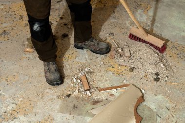 İnşaat atıklarıyla kaplı beton zeminde duran iş botları. Yenileme, işyeri güvenliği, sanayi ortamı, el işçiliği ve inşaat sonrası bakım kavramı